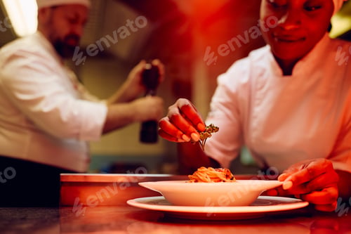 Preview: Close up of black cook serving a meal while working in the kitchen in restaurant.