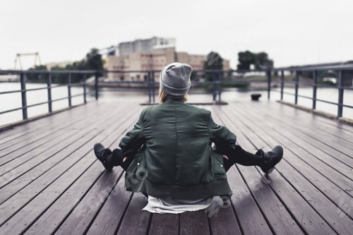 Preview: back view of stylish woman sitting on wooden pier