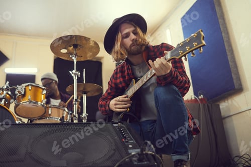 Preview: Guitarist Crouches Playing With Drummer in the Background