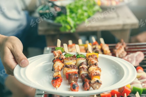 Preview: A man with a barbecue plate at a party between friends. Food, people and family time concept.