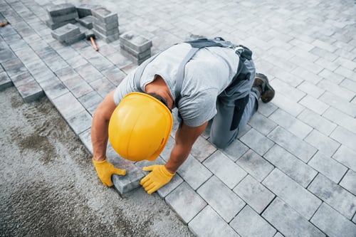 Preview: Concentrated at work. Man in yellow colored uniform have job with pavement