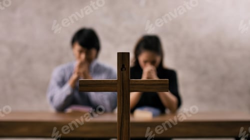 Preview: A young Asian Christian couple praying to Jesus Christ in a church.