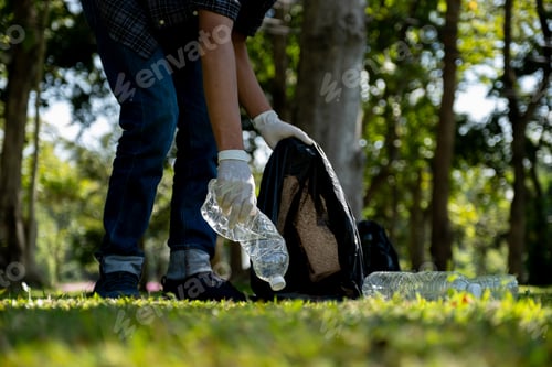 Preview: Hand holding plastic bottle waste, picking up trash and putting it in the black garbage bag at Park