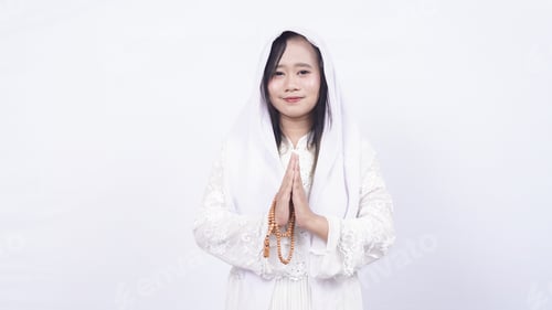Preview: Asian muslim woman wearing prayer beads welcoming guests / Ied Fitr Greeting in white background