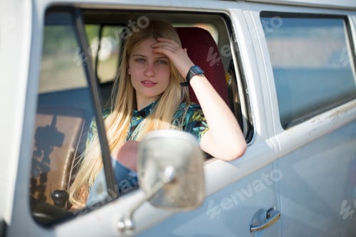Preview: Young woman gazing through a car window with a contemplative look.