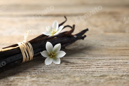 Preview: Bunch of vanilla pods and flowers on wooden table, closeup. Space for text