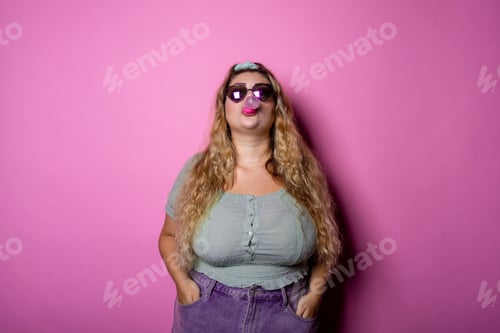 Preview: Caucasian chubby young woman blows bubble from chewing gum isolated over pink background