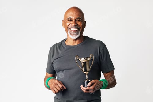 Preview: Sporty senior man holding a golden trophy