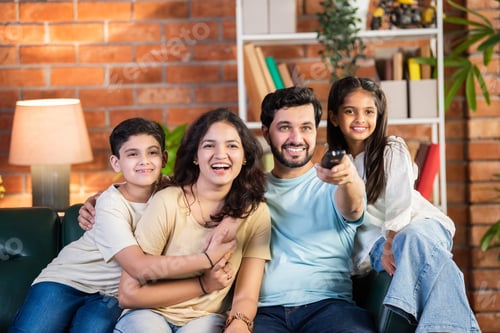 Preview: Happy Indian parents and kids sitting on a sofa, enjoying TV time together in the living room