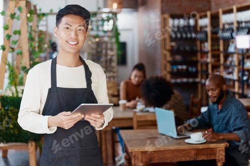 Preview: Portrait of smiling asian small business owner in his restaurant holding a wireless digital tablet.