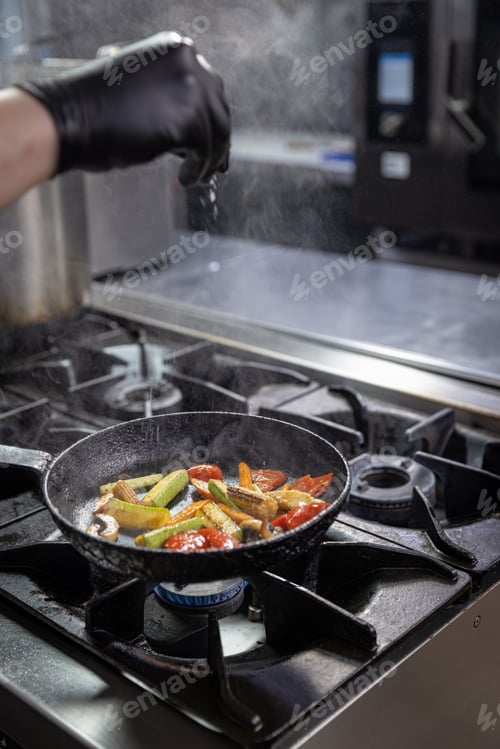 Preview: Chef adding salt into a pan of grilled vegetables