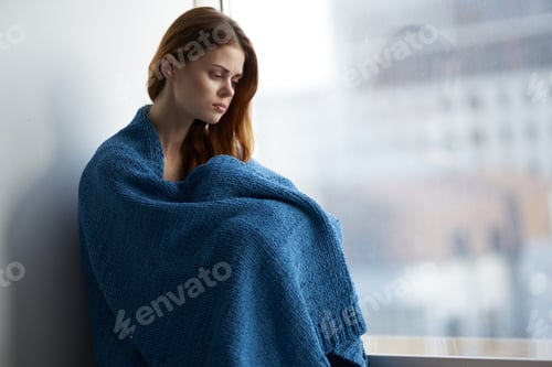 Preview: woman sitting near the window with a blue plaid smile at home