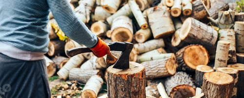 Preview: Man in jeans and checkered shirt standing near stump with ax in hands. long banner