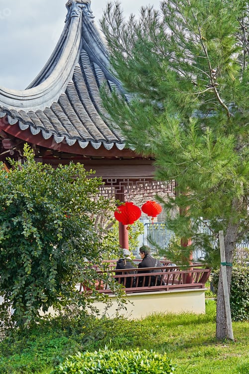 Preview: Romantic couple sitting in Chinese gazebo in garden with oriental red traditional lantern.
