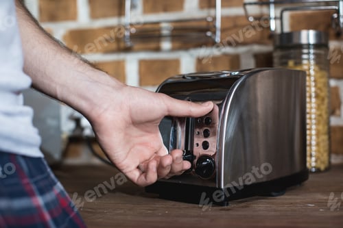 Preview: cropped shot of man turning on toaster while preparing toasts at morning