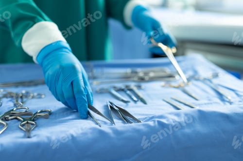 Preview: Midsection of surgical tech placing surgical tools on table in operating theatre