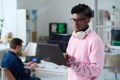 Preview: Young Black Man Using Laptop Computer in Office Workspace