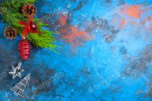 Preview: top view pine tree branches with pinecones red and silver hanging ornaments on blue-red background