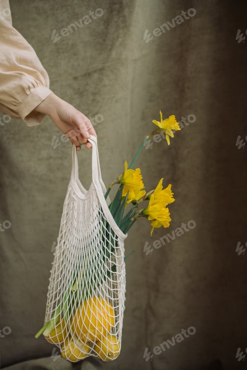 Hand Holding Mesh Bag with Lemons and Flowers