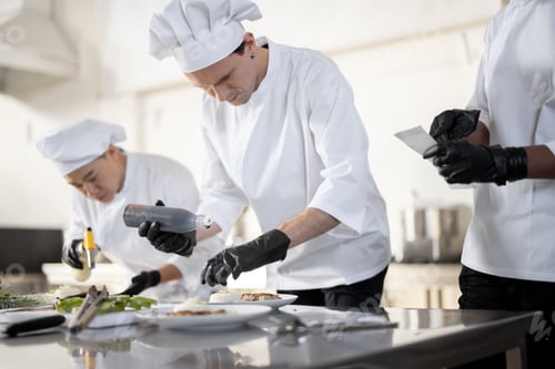Preview: Group of cooks finishing main courses while working together in the kitchen
