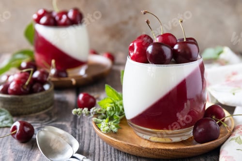 Preview: Panna cotta with sweet cherry jelly on a rustic table.
