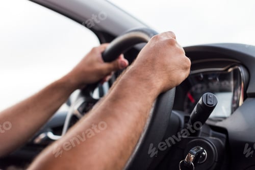 Preview: young man hands driving a car with both hands on the wheel