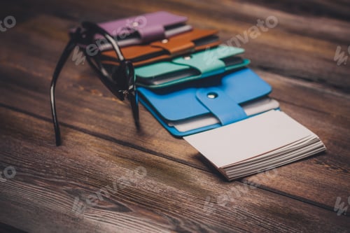 Preview: business card holder and glasses with black frames on the table a pack of white paper