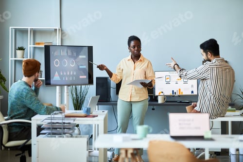 Preview: Young confident female business coach pointing at screen with graphic data