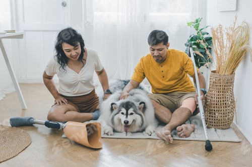 Preview: Couple bonding and smiling while sitting near dog in at home.