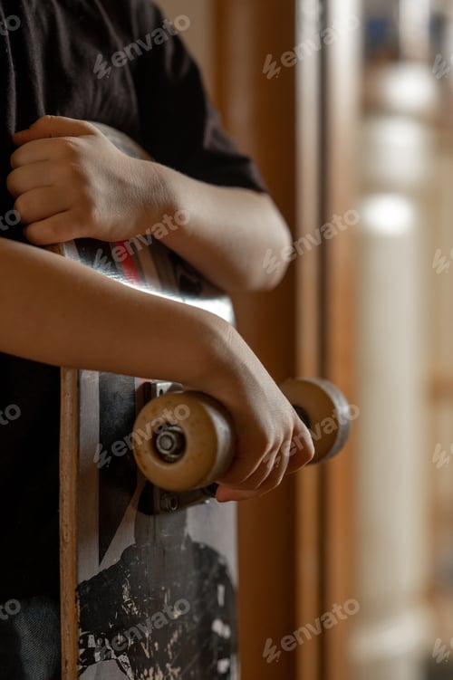 Preview: Detail. The boy is holding a skateboard