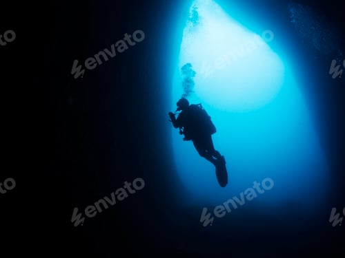 Vista previa: silueta de un buceador buceando en una cueva oscura