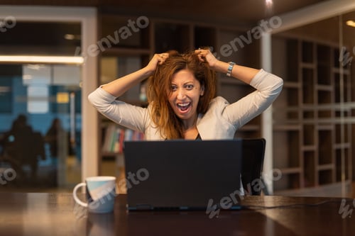 Preview: Angry and frustrated woman using laptop computer in office