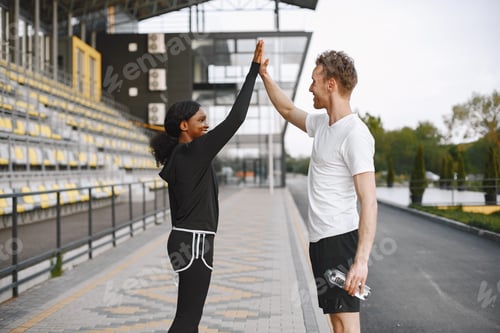Preview: African-american woman and caucasian man give a high five while training