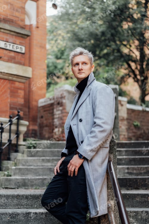 Preview: Handsome male model with gray hair in a black roll neck jacket and trousers, checked coat walking