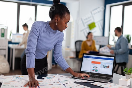 Preview: African woman scorlling on laptop looking at charts