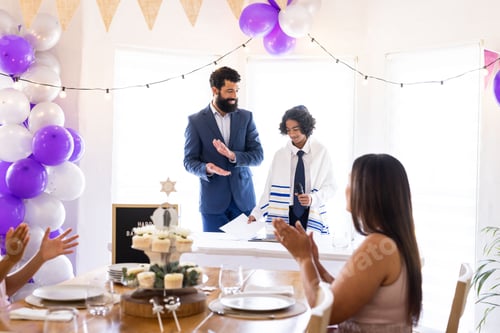 Preview: Father and son celebrating Bar Mitzvah with family, clapping and smiling together