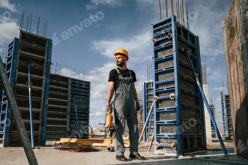 Preview: Standing with grinding machine in hands. Man in uniform is working on the construction site