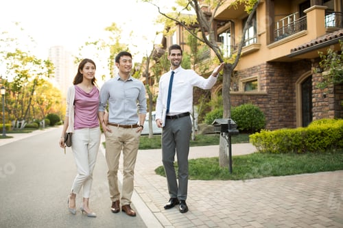 Preview: Happy young Chinese couple talking with confident businessman