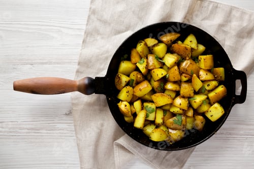 Preview: Homemade Roasted Potatoes with Mustard Seeds in a cast-iron pan, top view. Flat lay, overhead