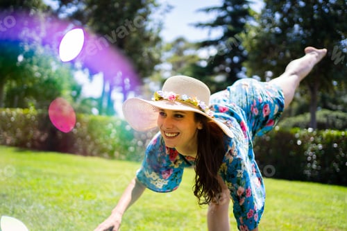 Preview: Woman with a hat dancing in a garden next to soap bubbles