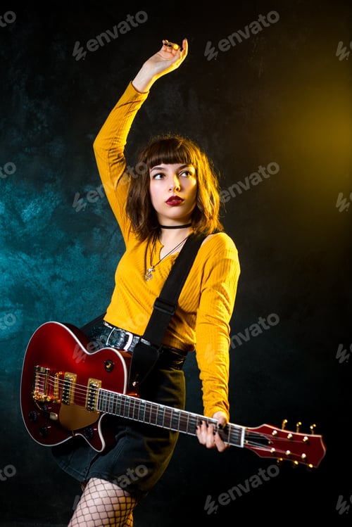 Preview: Portrait of beautiful young hipster woman with curly hair with red guitar in neon lights.