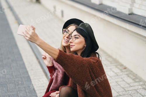Preview: Two attractive girls making selfie while sitting together
