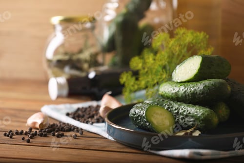 Preview: Fresh cucumbers and other ingredients prepared for canning on wooden table, closeup. Space for text