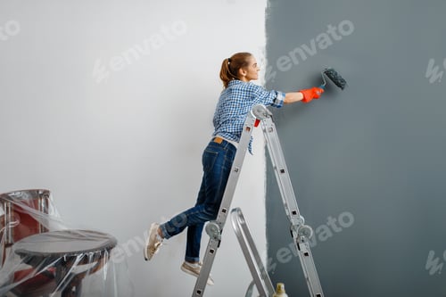 Preview: Female house painter in gloves paints the wall
