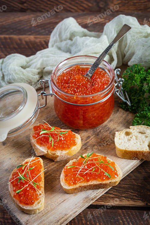Preview: Delicious fresh red caviar with baguette toasts on wooden background