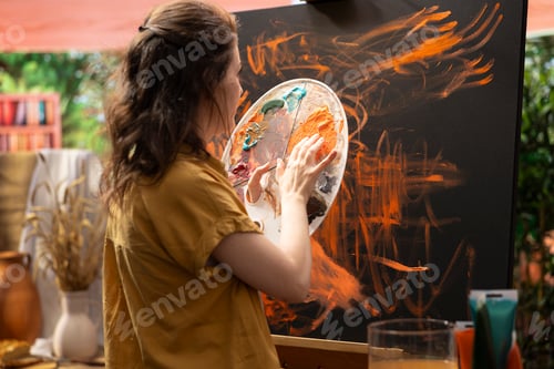 Preview: Confident artist stands before an easel and painting with her fingers