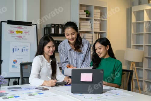 Preview: Young Asian Businesswomen Collaborating in Modern Office Environment with Laptops and Charts