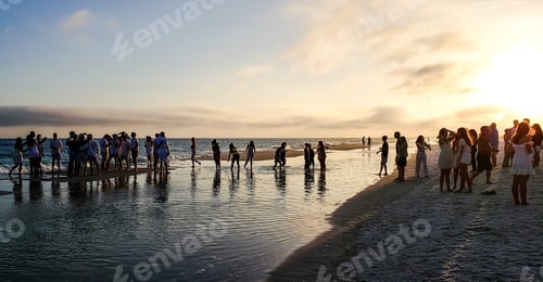 Preview: Groups of friends on beach at sunset celebration of high school graduation.