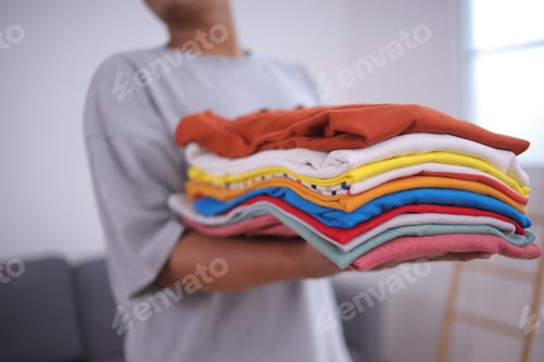 Preview: Stack of Colorful Folded Laundry Being Held Indoors
