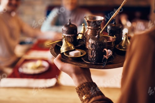 Preview: Close-up of woman serving traditional Turkish coffee with dessert at home.